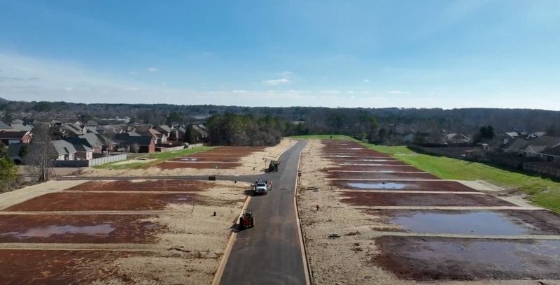 Aerial view of Creekside Commons residential development with graded lots and a newly paved road.